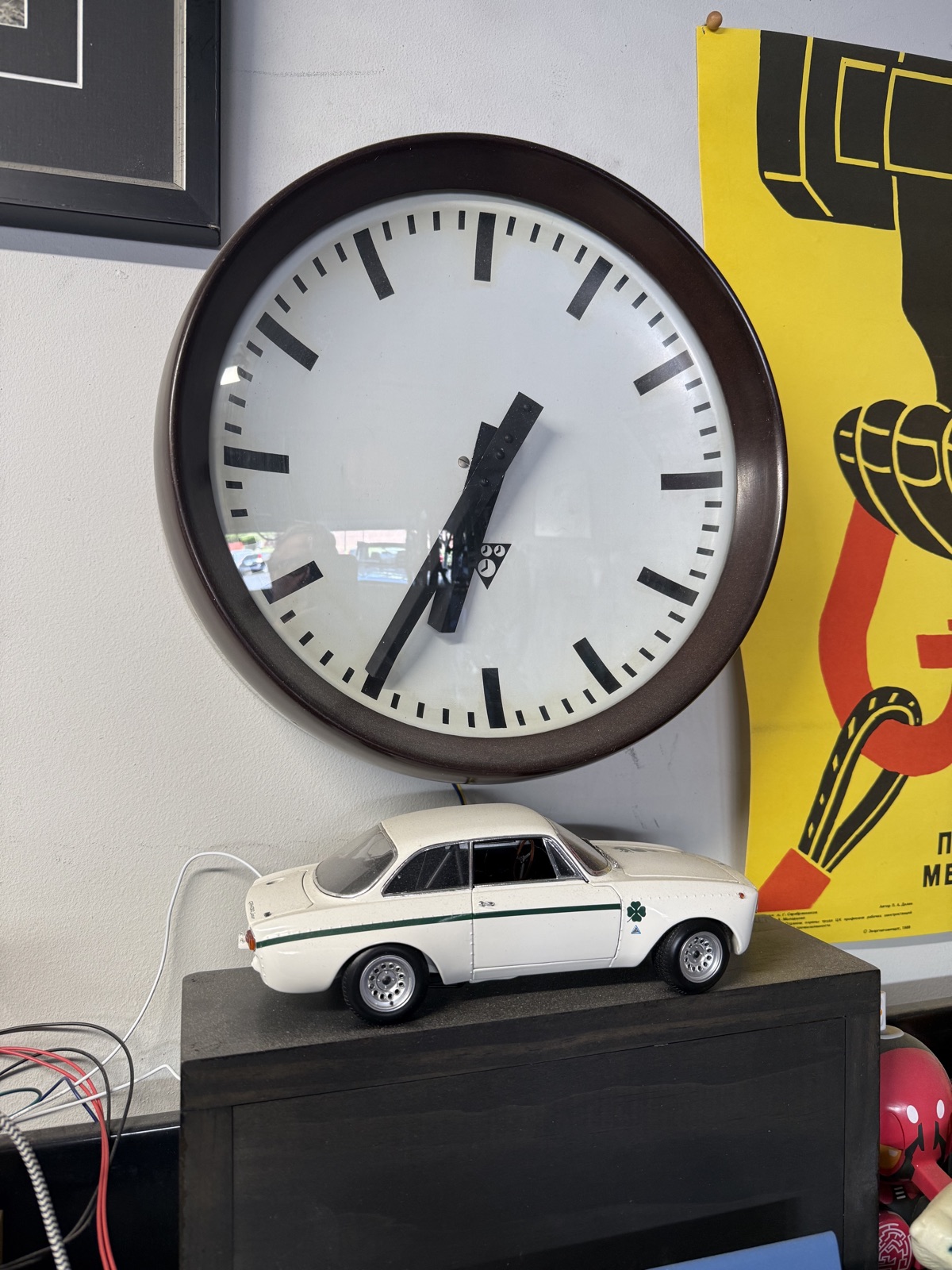 Vintage Pragotron slave clock mounted on a wall, showing time just before 11:30.